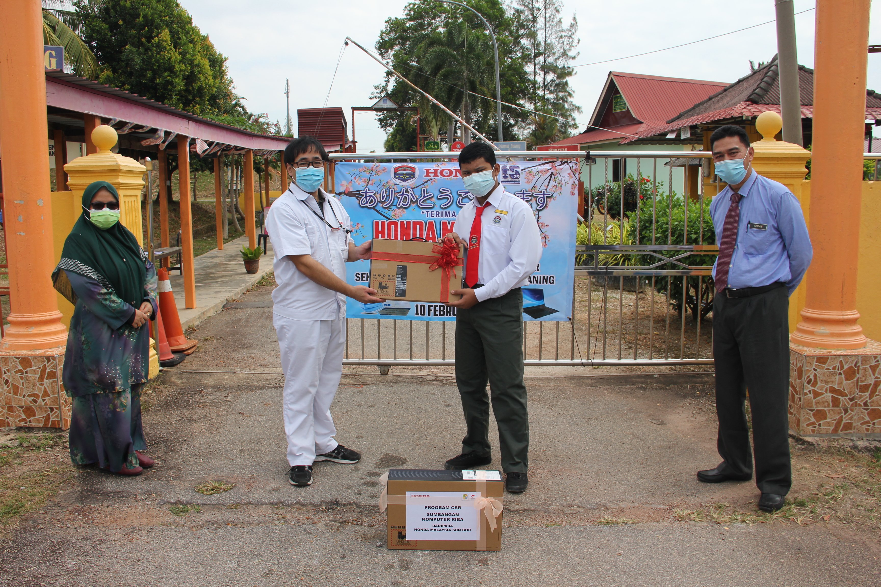 Representative of Honda Malaysia handing over the laptops to a representative student with the presence of teachers from the school